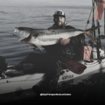 Rijavec sosteniendo pescado en su kayak